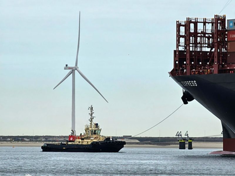 pala-eolica-sullo-sfondo-di-un-rimorchiatore-che-traina-una-portacontainer–1grpi